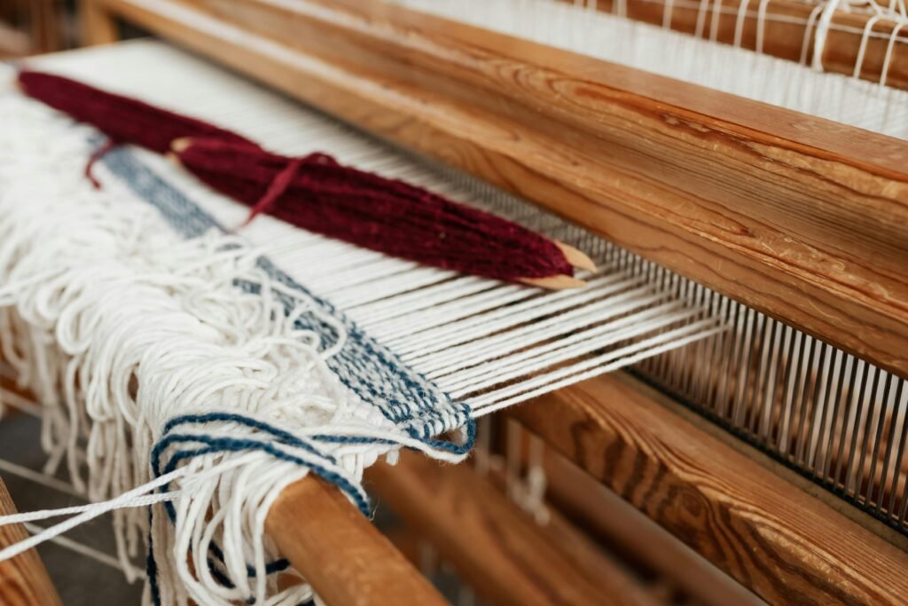 Plan détaillé d'un métier à tisser en bois avec des fils blancs et bleus dans un processus de tissage.